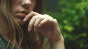 the lower half a a woman, with her hand up to her chin in a pensive look