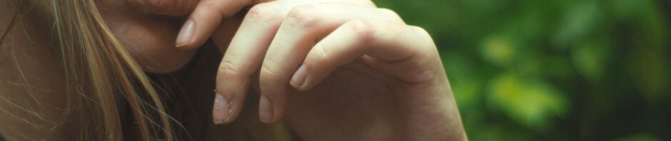 the lower half a a woman, with her hand up to her chin in a pensive look